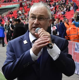 Brian Porter speaking into a microphone at AFC Fylde